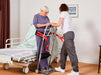 Elderly woman using sit to stand device with caregiver using assist sleeve to help patient stand 